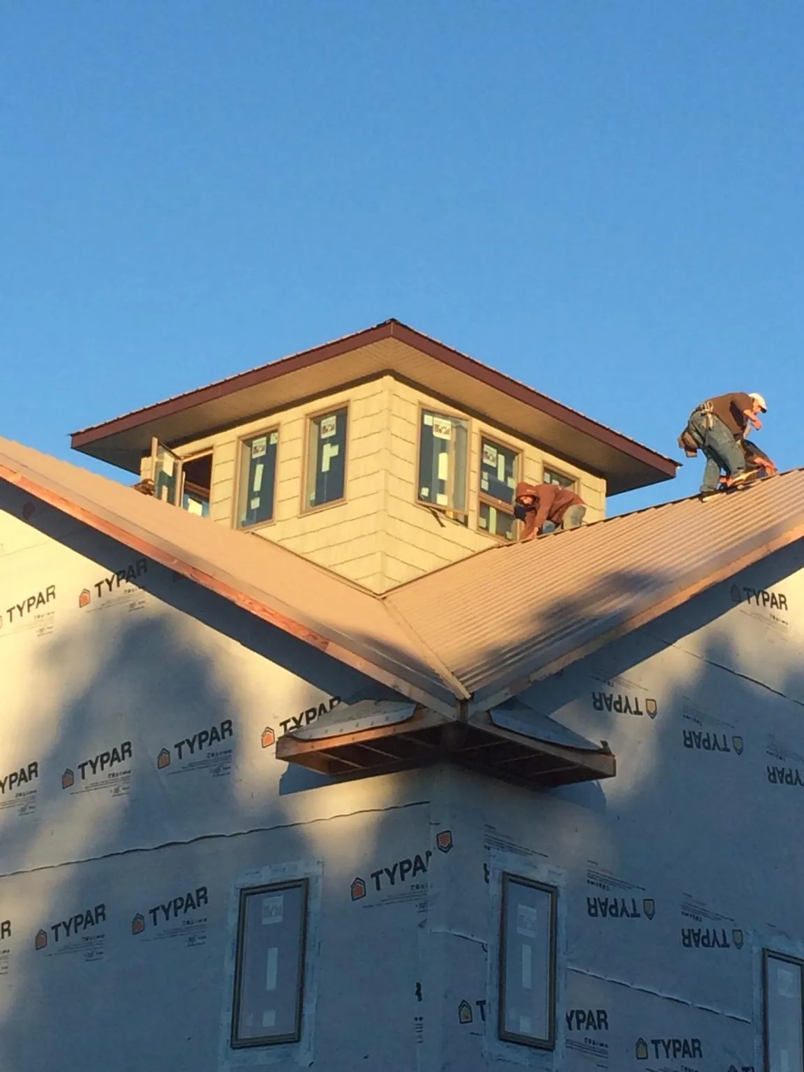 Roofers working around a rooftop cupola on a new metal roof at sunset — Roof Waterproofing in Centreville by Roofing Brothers